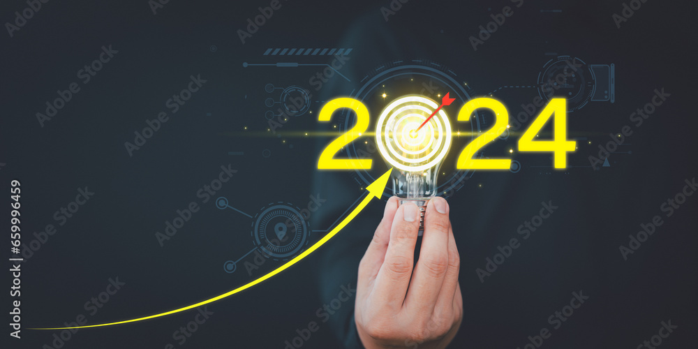 Businessman holding a light bulb with goal icon and the year 2024, drawing line for increasing arrow. Business planning and strategy innovative business vision and new year resolution target concept