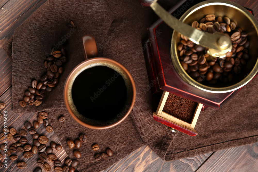 Cup of coffee with grinder and beans on wooden background