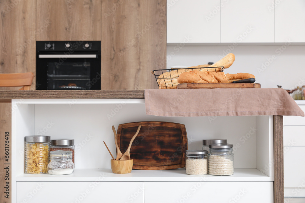 Cutting board with fresh baguette on table in interior of light kitchen