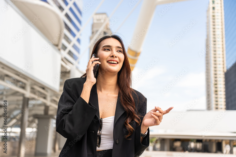 Asian young businesswoman talking on smartphone while walking in city. 