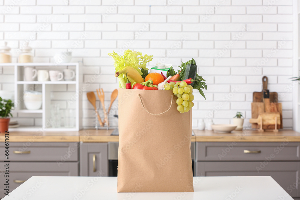 Shopping paper bag with fresh products on table in kitchen