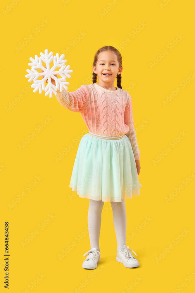 Cute little girl in warm sweater with snowflake on yellow background
