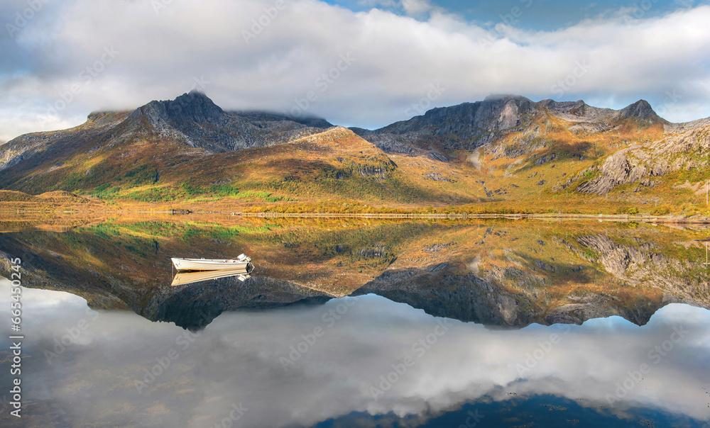 wonderful mountainous landscape in Norway reflected on the water surface with a small rowboat