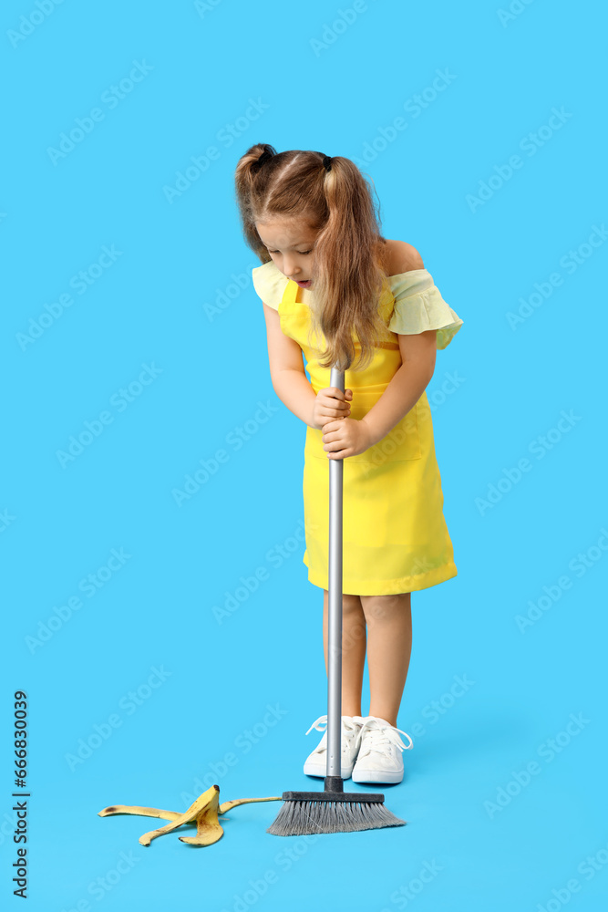 Cute little girl with broom and banana peel on blue background