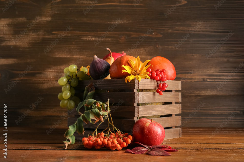 Box with different fresh fruits, berries and pumpkin on wooden background