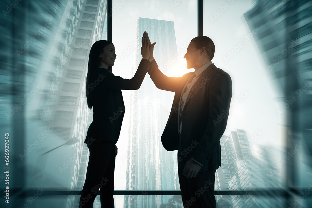 Young businesspeople silhouettes hi-fiving while standing on creative corporate interior background with panoramic windows and city view. Teamwork, job, success and career concept. Double exposure.
