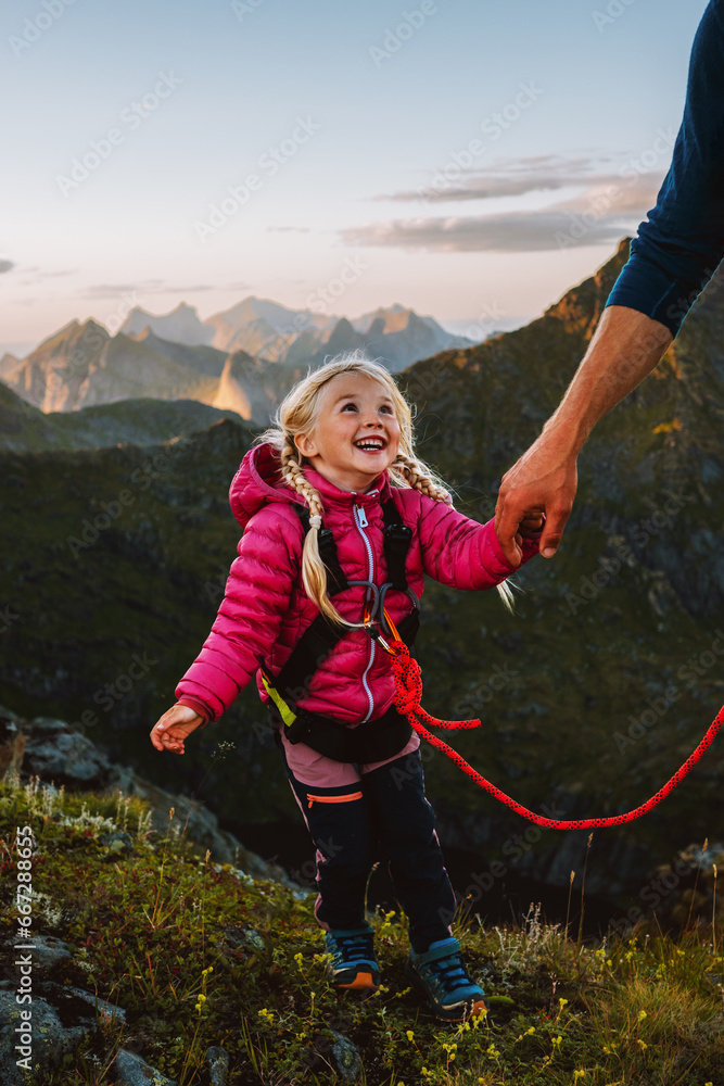 Child girl hiking with father holding hands in mountains of Norway adventure travel family vacations outdoor active healthy lifestyle 4 years old kid happy smiling