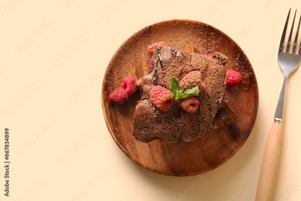 Wooden plate with pieces of raspberry chocolate brownie on orange background