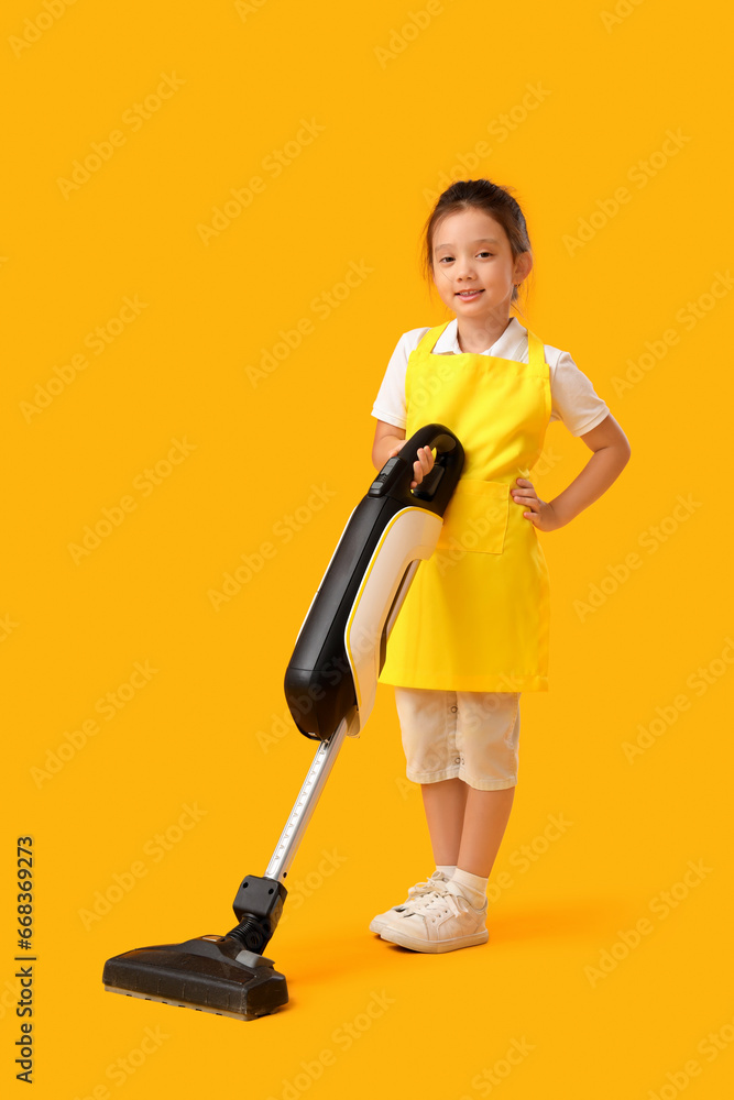 Cute little janitor with vacuum cleaner on yellow background