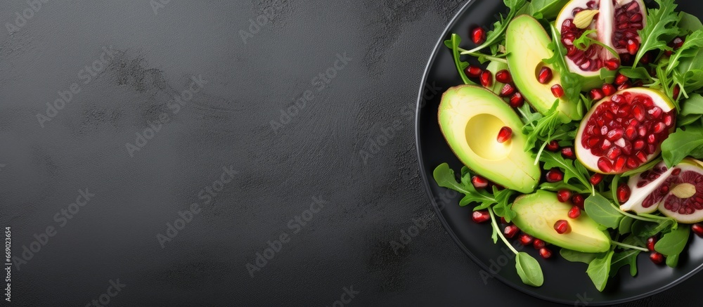 Avocado salad with greens arugula spinach and pomegranate on a gray plate Healthy vegan food clean eating top view