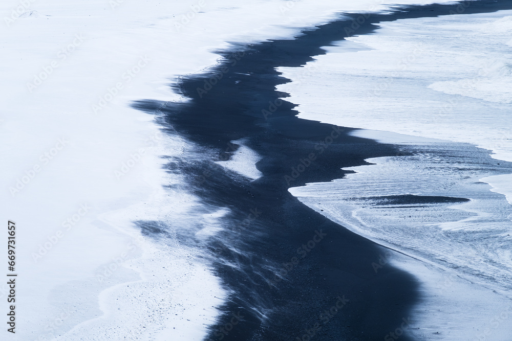 Seashore. View of stormy sea, black volcanic sand and snow. Landscape in Iceland. Winter view. Abstract natural landscape.
