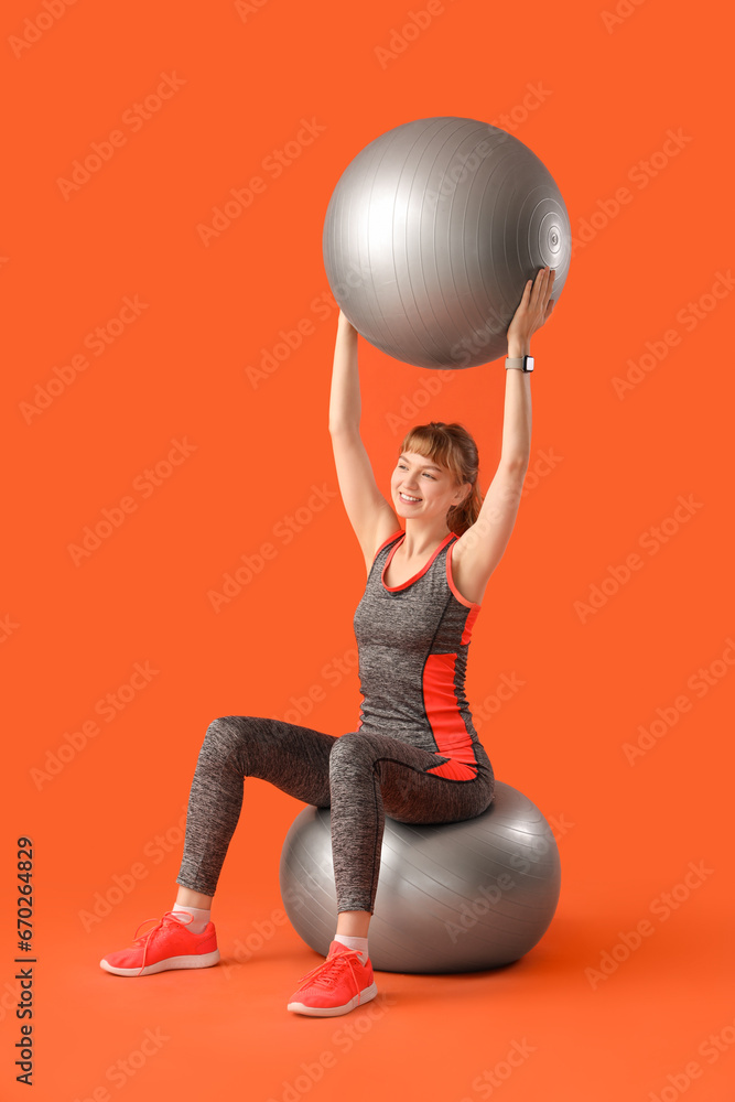 Young sporty woman with fitness balls on red background