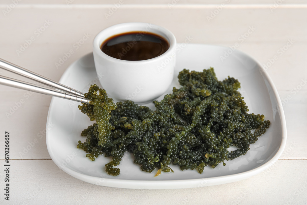 Plate with healthy seaweed and soy sauce on light wooden background