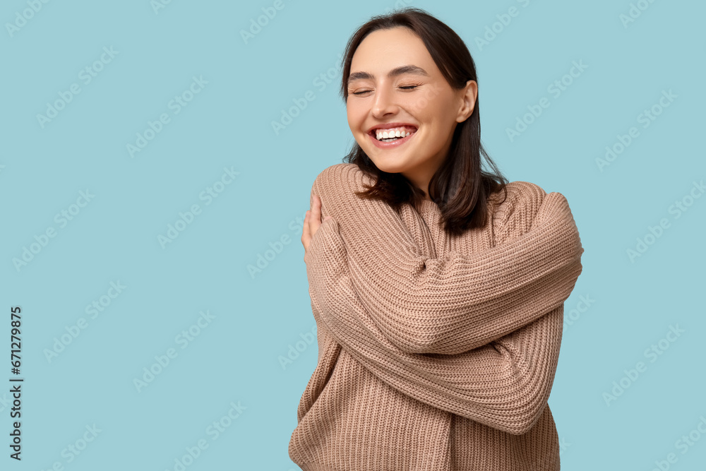 Young woman hugging herself on blue background