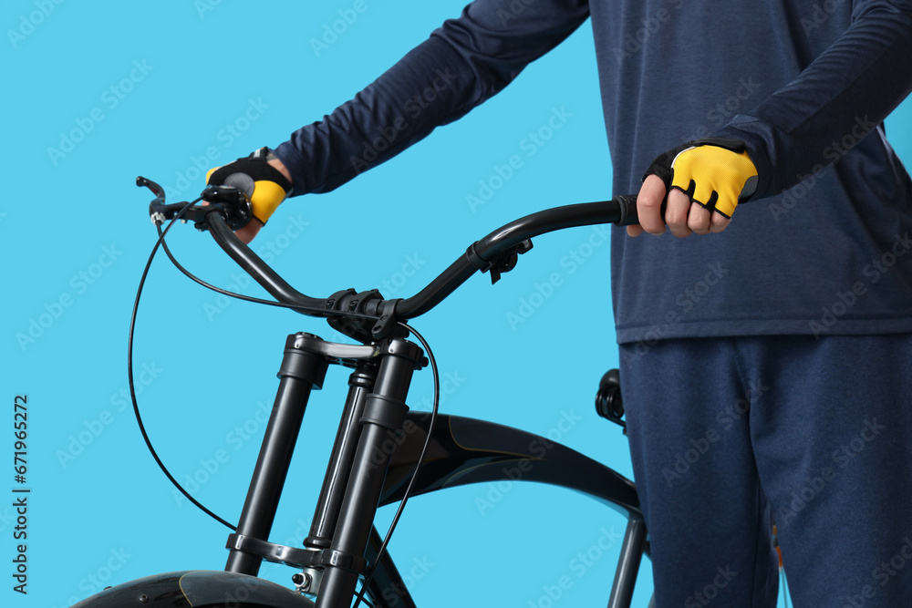Young man with bicycle on blue background
