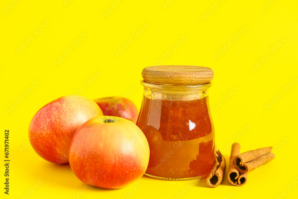 Jar of sweet apple jam with cinnamon on yellow background