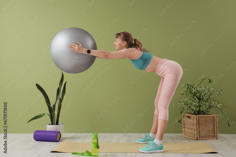 Young sporty woman training with fitness ball at home
