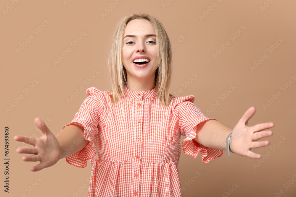 Young woman opening arms for hug on beige background