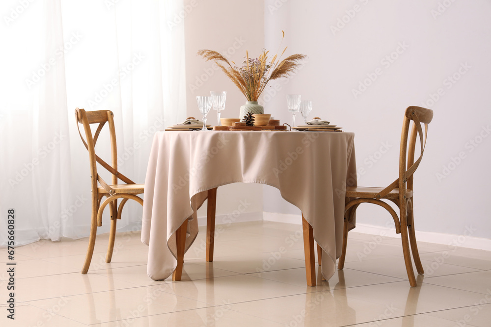 Elegant table setting with dried flowers, pampas grass and pine cones in light dining room