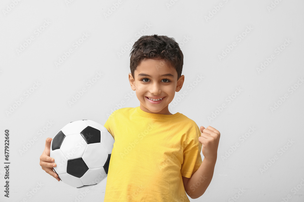 Happy little boy with soccer ball on white background