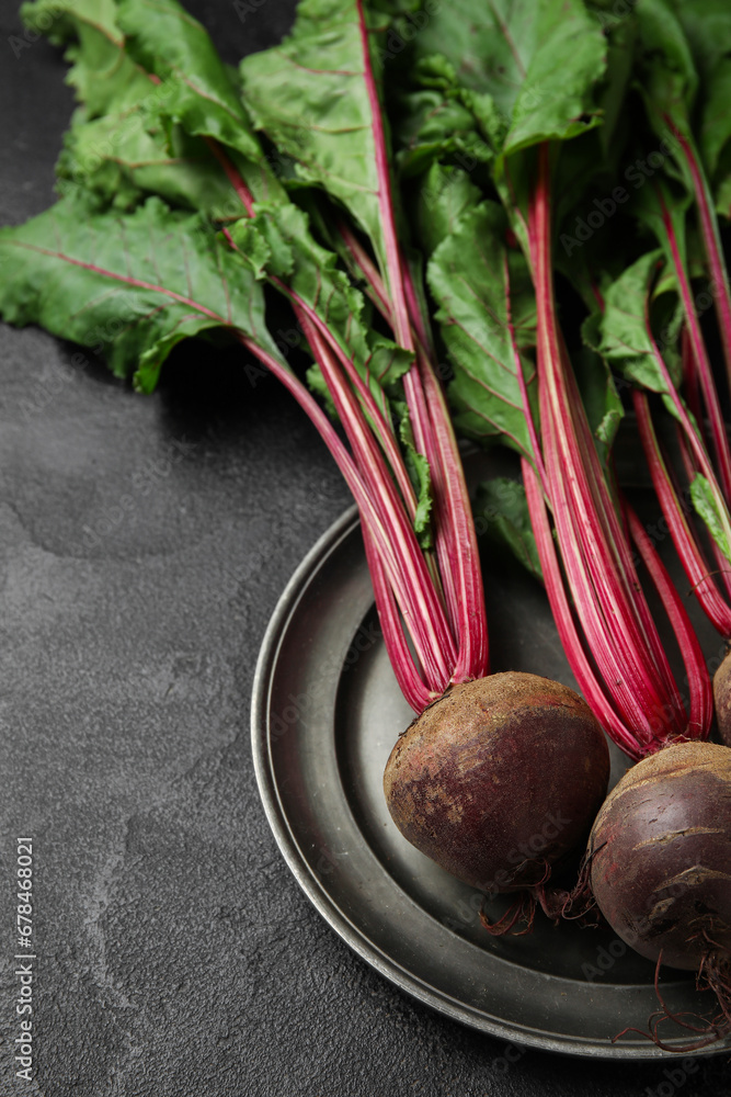 Plate with fresh beetroots on black table