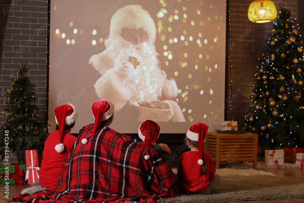 Happy family watching Christmas movie on projector screen at home, back view