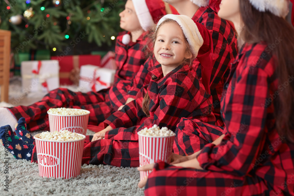Little girl with popcorn and her family watching Christmas movie at home