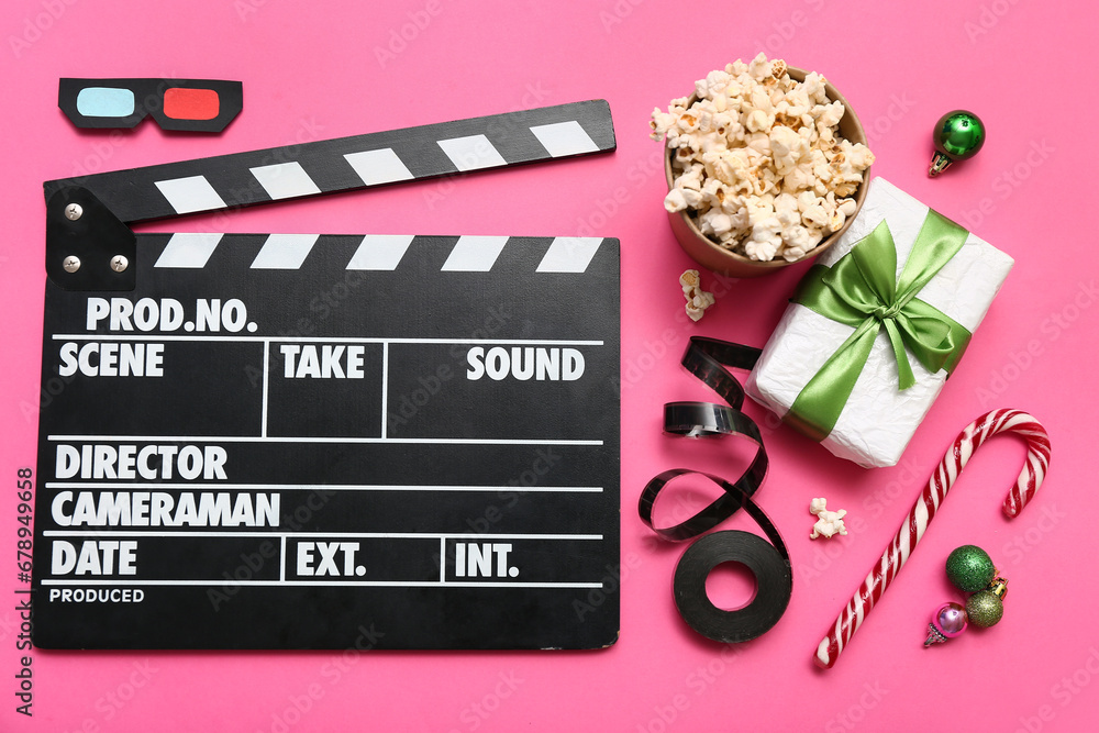 Movie clapper with popcorn, film reel and Christmas decor on pink background