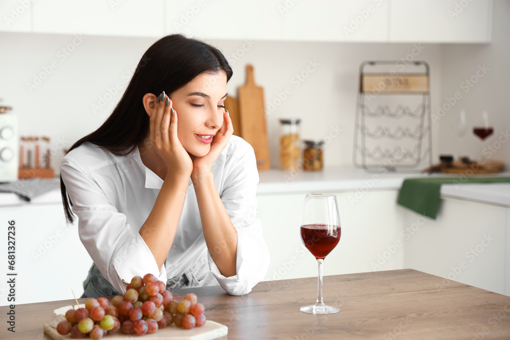 Young woman with glass of wine in kitchen