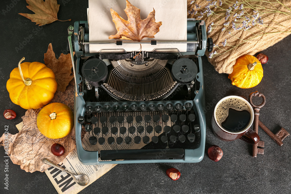 Vintage typewriter, pumpkins, chestnuts, cup of coffee, keys and autumn leaves on black background