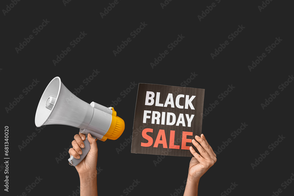 Female hands holding poster with text BLACK FRIDAY SALE and megaphone on dark background
