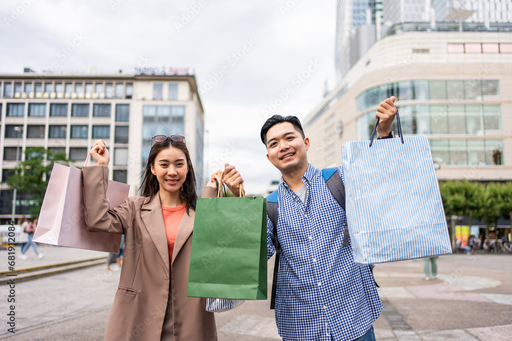 Portrait of Asian couple shopping goods outdoors in department store.